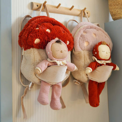 Two plush dolls with red and pink outfits hanging on a rack.