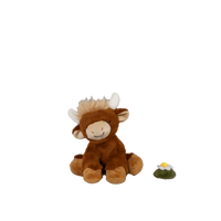 Plush toy cow with a small plant on a white background