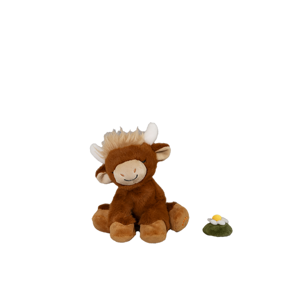 Plush toy cow with a small plant on a white background