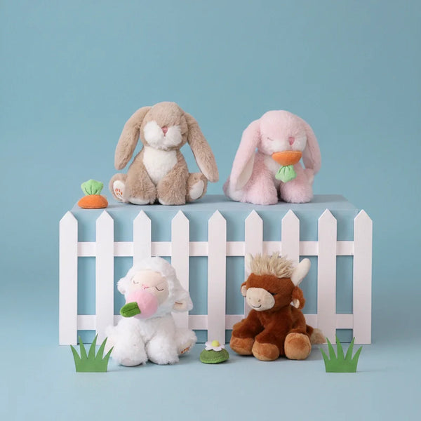 Four plush toys on a blue background with a white picket fence and small plants.