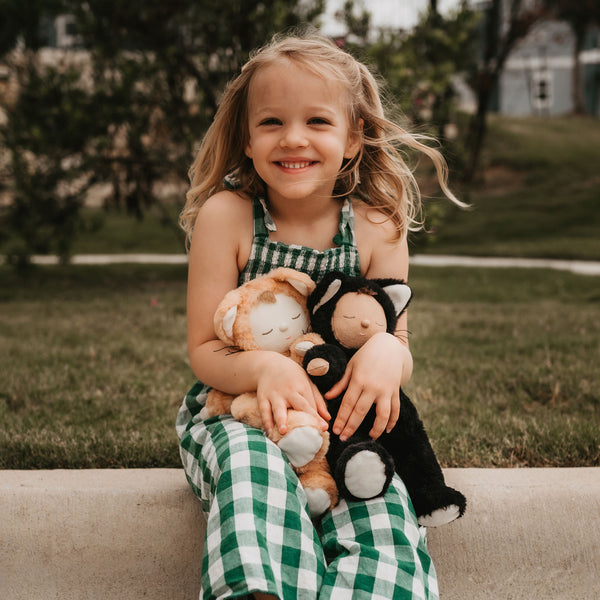 Image of a little girl loving a black cat and a tabby cat, soft plush toy doll for kids