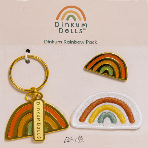 Dinkum Dolls rainbow-themed keychain, patch, and enamel pin on a beige background.