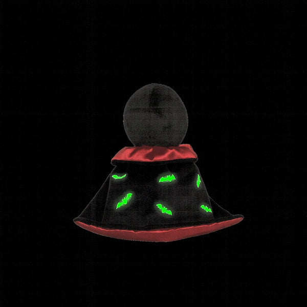 Black and red hat with green glowing eyes on a black background