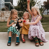 Image of 3 little girls playing with a black cat, soft plush toy doll for kids