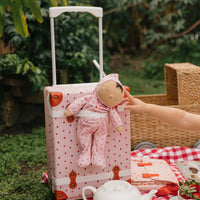 Soft-doll with pink strawberry printed onesie, perfect as a childs travel companion strapped to our see-ya suitcase.