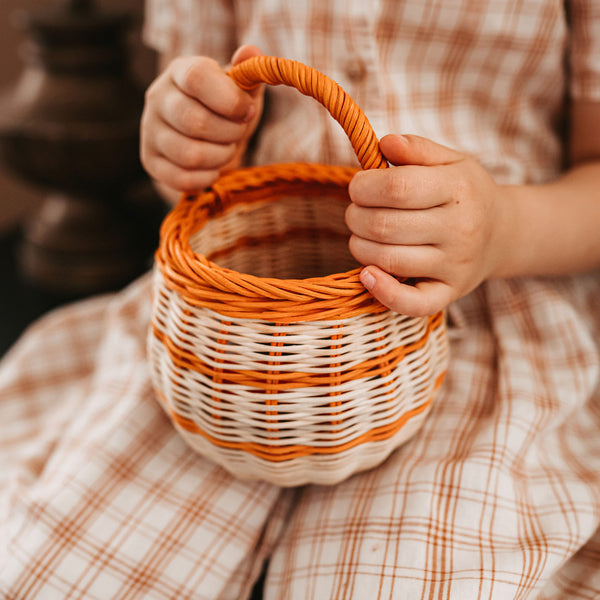 Olli Ella Halloween Berry Basket with orange stripe held by a child