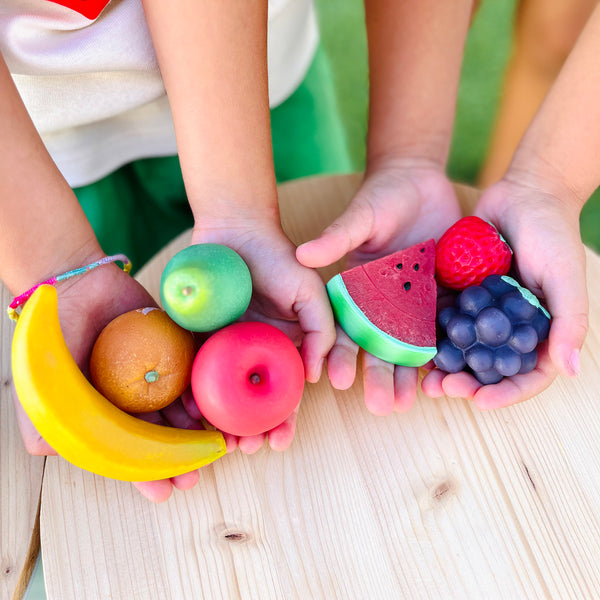 Olli Ella Tubbles Sensory Stones Fruit Fantastique tenu dans les mains des enfants