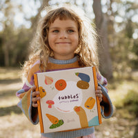 Olli Ella Tubbles Sensory Stones Vibrant Veggies packaging held in childs hands